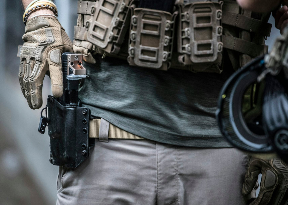 Person wearing tactical gear with a gun holster and weapon